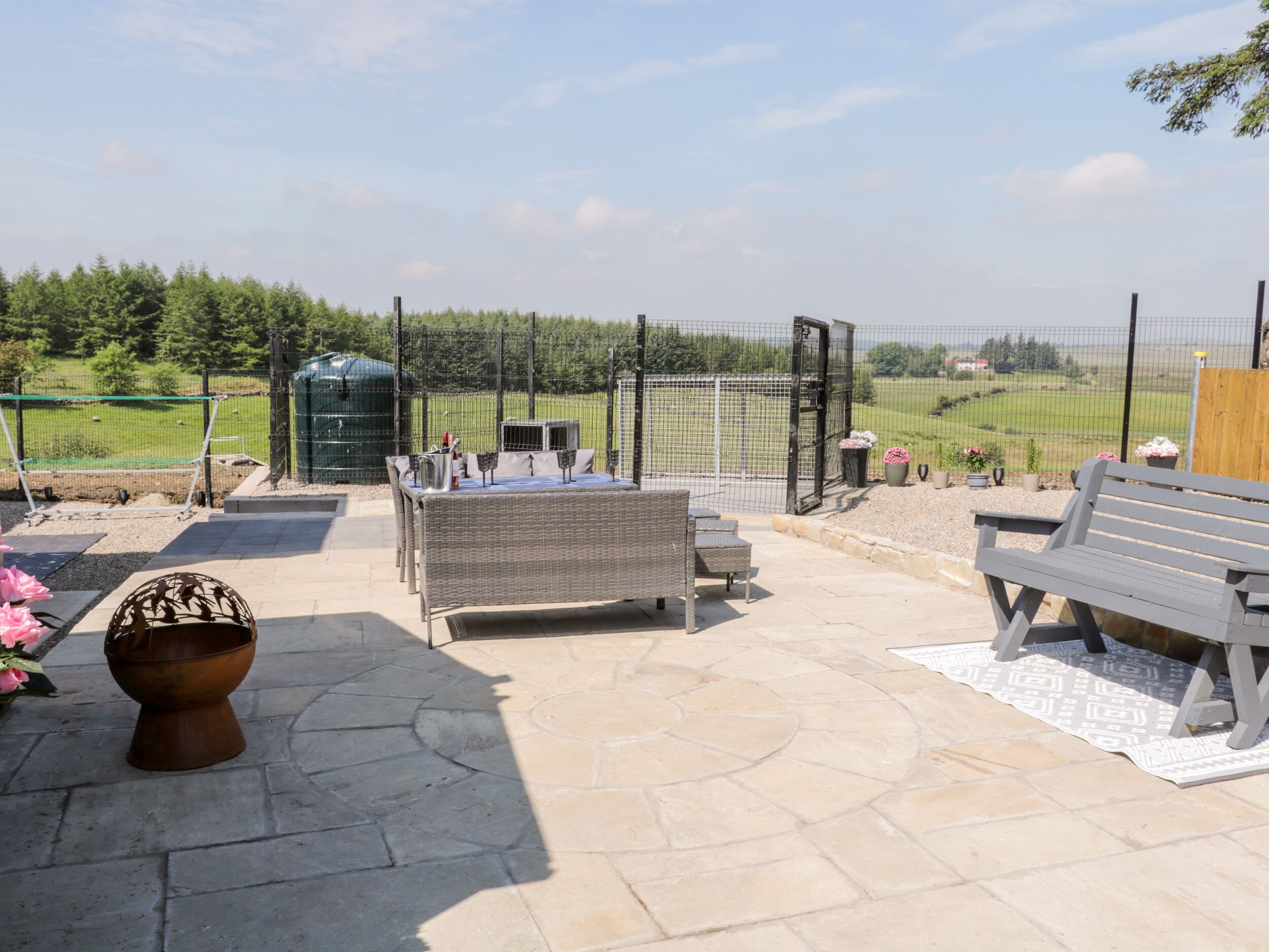An outdoor patio with a table and chairs, a bench, and a decorative pot.