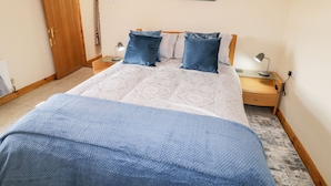 A bedroom with a bed, two bedside tables, a nightstand, a clock, and a painting of the aurora borealis. - Peter's Farmhouse (Cookstown)