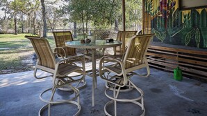 A round table with four wicker chairs, a glass top, and a metal frame.