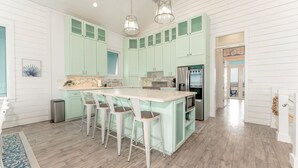 A kitchen with a central island, bar stools, and a stainless steel refrigerator.