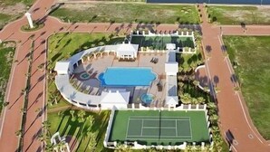 An aerial view of a resort with a swimming pool, tennis court, and landscaped areas. - Avalon - Townhouse At The Shores 4 Bedroom Home by RedAwning (South Padre Island)