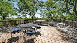 Een terras buiten met een ronde tafel en stoelen, omgeven door bomen.