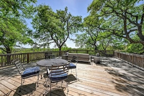 An outdoor deck with a round table and chairs, surrounded by trees. - Luxury 23-ac Ranch Hot Tub and Hill Country Views! (Fredericksburg)