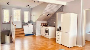 A compact kitchen with a built-in oven, a refrigerator, and a small dining area.