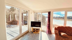 A spacious living room with large windows, a flat-screen TV, and a comfortable sofa.