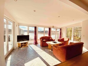 A spacious living room with large windows, a flat-screen TV, and a sofa set. - Bjurvik's Villa - Flat 3 - Business Customers Only (Flen)