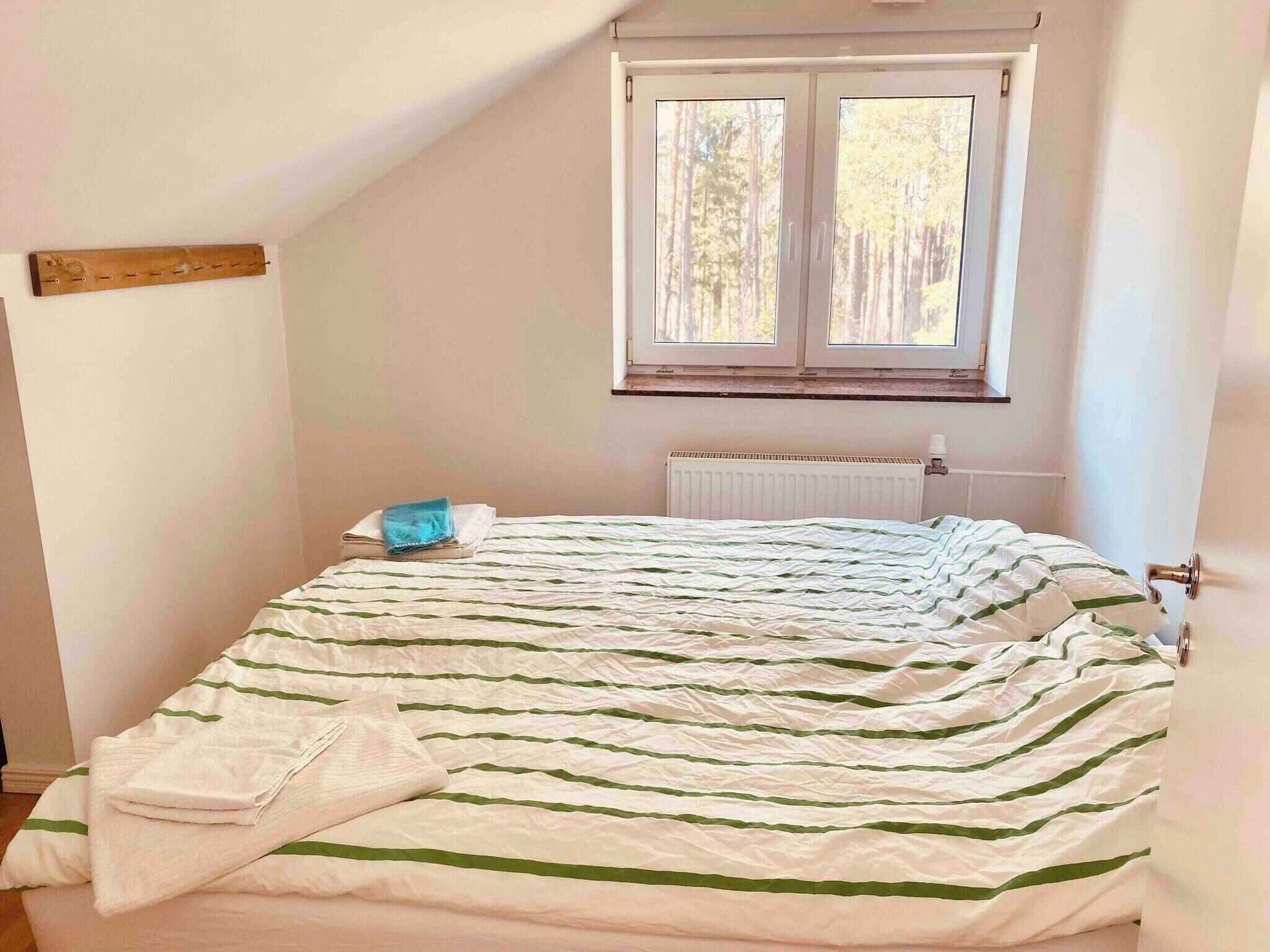 Una camera da letto con un letto, una finestra, un termosifone e una mensola in legno.