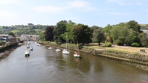 A river with boats docked along the banks, surrounded by greenery and buildings. - The Loft Cottage (Totnes)