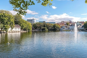 A lake with a fountain, surrounded by trees and buildings, including a hotel. - Charming Rooftop Apartment In Heart Of Stavanger (Stavanger)