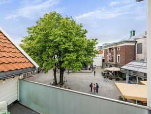 A courtyard with a large tree, cobblestone ground, and buildings with brick facades. - Charming Rooftop Apartment In Heart Of Stavanger (Stavanger)
