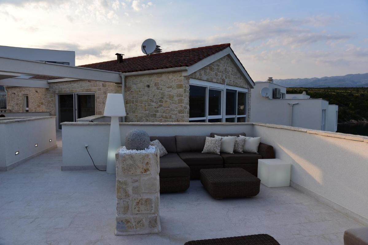 Una terraza en la azotea con paredes de piedra, un pilar de piedra, un conjunto de sofás y una lámpara.