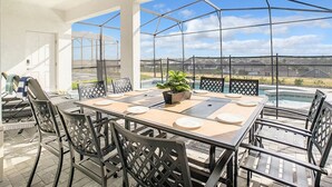 A covered patio with a table and chairs, a ceiling fan, and a view of a swimming pool and houses. - Windsor Island 7br, Free Pool Heat, 5min Walk To L (Davenport)
