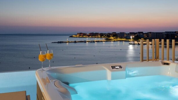 A hot tub with a view of the sea and buildings at dusk. - Salt&soul Residence Three-bedroom Apartmant (Povljana)
