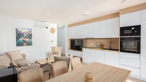 A modern kitchen with white cabinets, a wooden countertop, and a built-in oven. - Salt&soul Residence Three-bedroom Apartmant (Povljana)