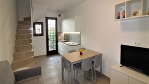 A modern apartment with a staircase, a dining area with a TV, and a kitchen. - Relaxing Villa With Shared Pool (Lignano Sabbiadoro)