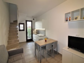 A modern apartment with a staircase, a dining area with a TV, and a kitchen. - Relaxing Villa With Shared Pool (Lignano Sabbiadoro)