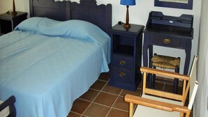 Un dormitorio con cama, dos mesitas de noche con lámparas, una silla, cómoda y espejo.