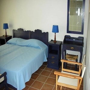Un dormitorio con cama, dos mesitas de noche con lámparas, una silla, cómoda y espejo.