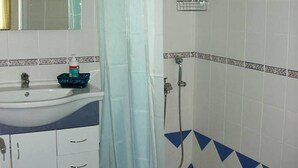 Un baño con lavamanos, espejo, ducha y paredes de azulejos.