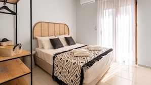 A bedroom with a bed, a hanging light fixture, a window with curtains, and a wooden floor. - Villa Ismini 3 Bedrooms With Pool , sea View and E-car Charger (Rethymno)