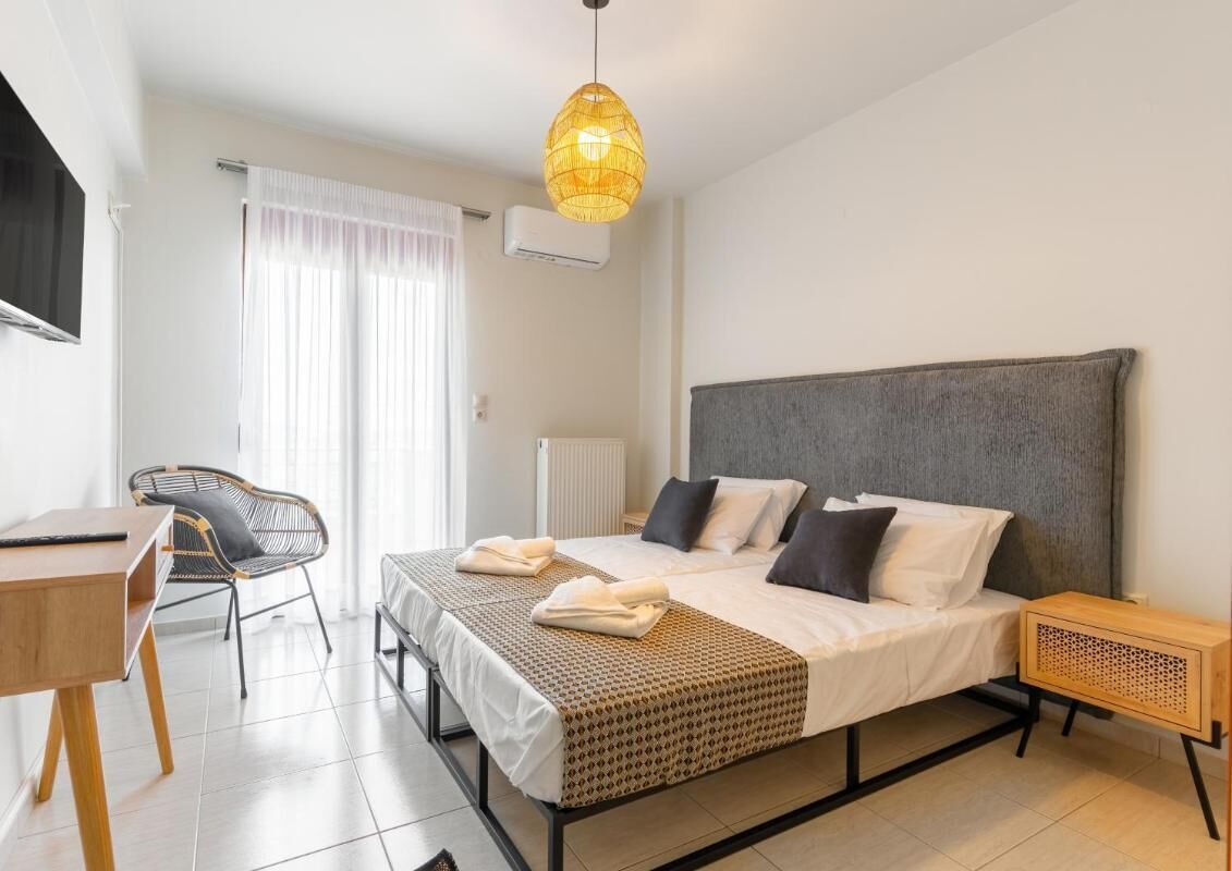 Een hotelkamer met een bed, een bureau, een stoel, een nachtkastje en een hanglamp.