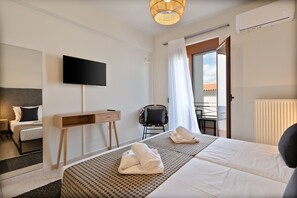 Ein modernes Hotelzimmer mit Bett, Schreibtisch, Sessel, Fernseher und einem Balkon mit Blick.