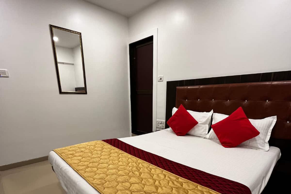 A hotel room with a large bed, a wooden headboard, and a mirror on the wall.