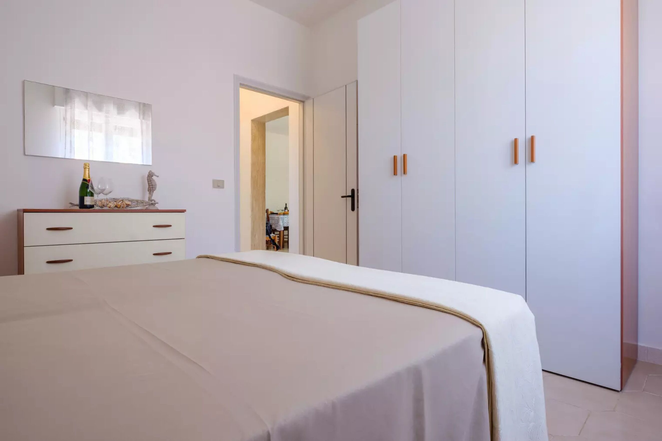 Um quarto com cama, penteadeira, espelho e guarda-roupa.