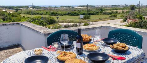 Una mesa al aire libre con comida, vino y una vista panorámica.