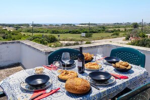 A table set outdoors with food, wine, and a scenic view. - Villa Punta Prosciutto Sea View Sea Front (Porto Cesareo)