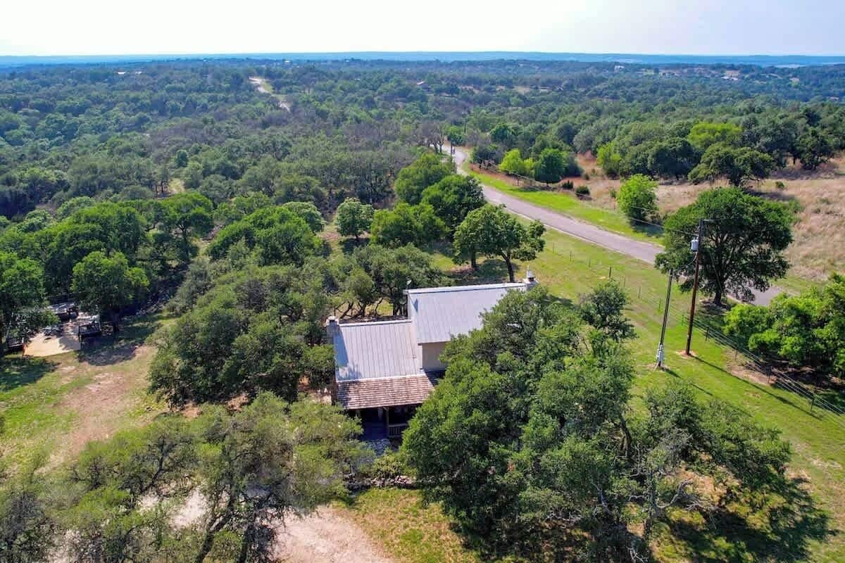 Una casa rodeada de un bosque frondoso, con un camino despejado que lleva a ella.
