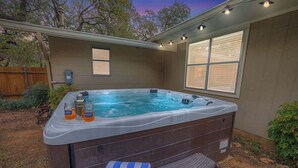 A hot tub with a wooden exterior, two windows, and a towel on the side. - The Billie Goat Haus - Hot Tub -steps to Main St! (Fredericksburg)