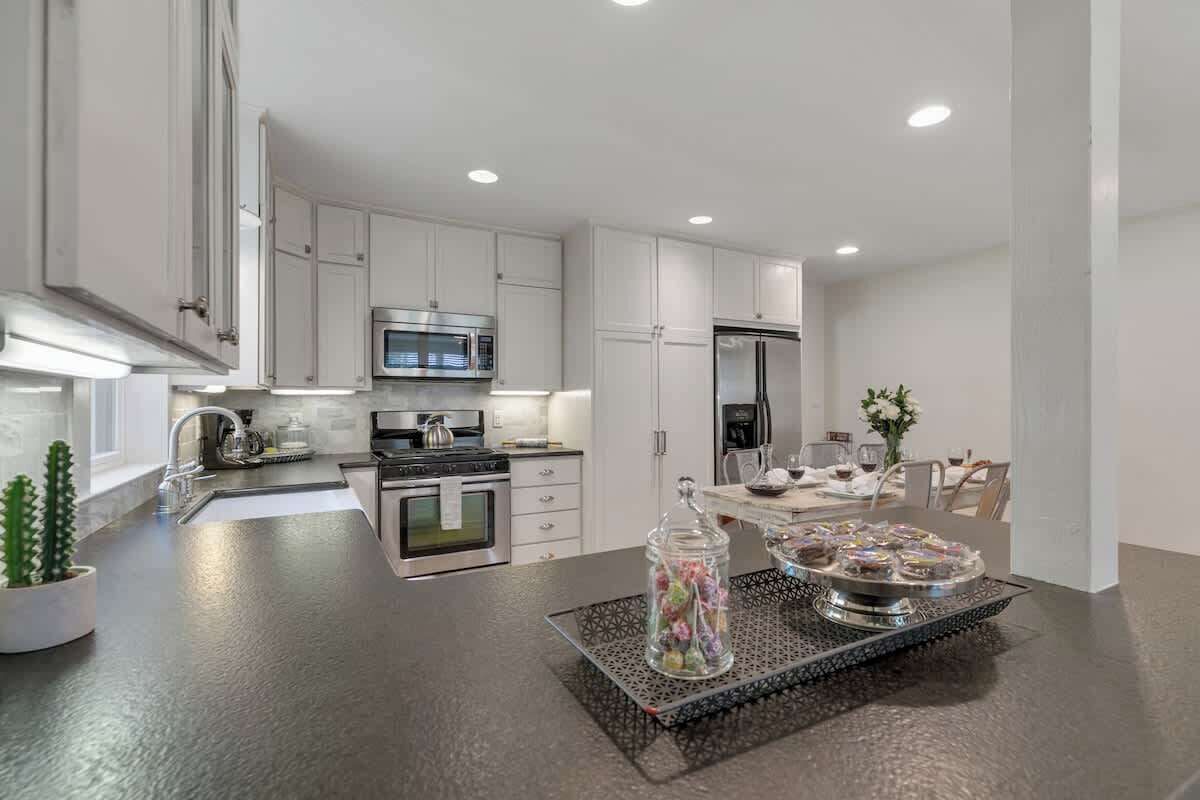 A modern kitchen with white cabinets, stainless steel appliances, and a central island with a glass jar of candies.