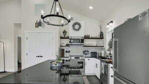 A modern kitchen with a large island, stainless steel appliances, and a black countertop. - Hill Country Hideaway With Fire Pit and Hot Tub! (Fredericksburg)