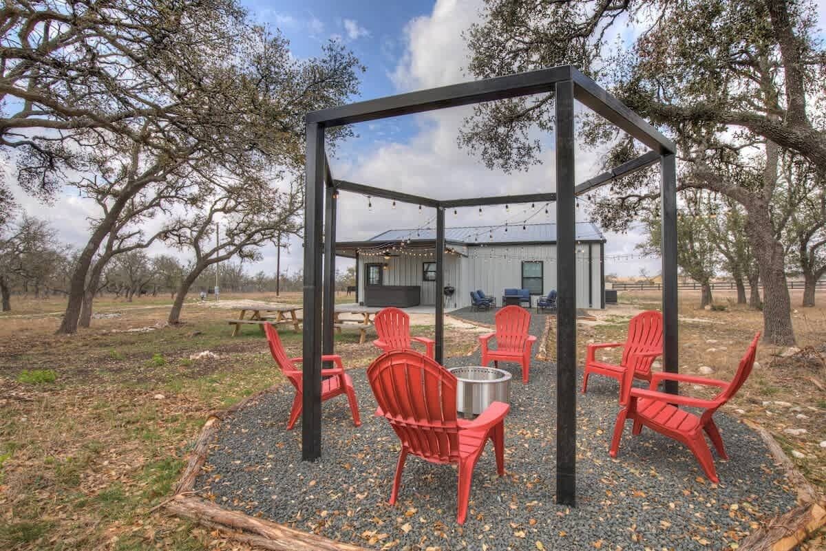 A gazebo with red chairs and a fire pit in a park setting.