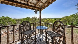 Une terrasse extérieure avec deux fauteuils en osier et une petite table, offrant une vue sur un paysage naturel arboré.