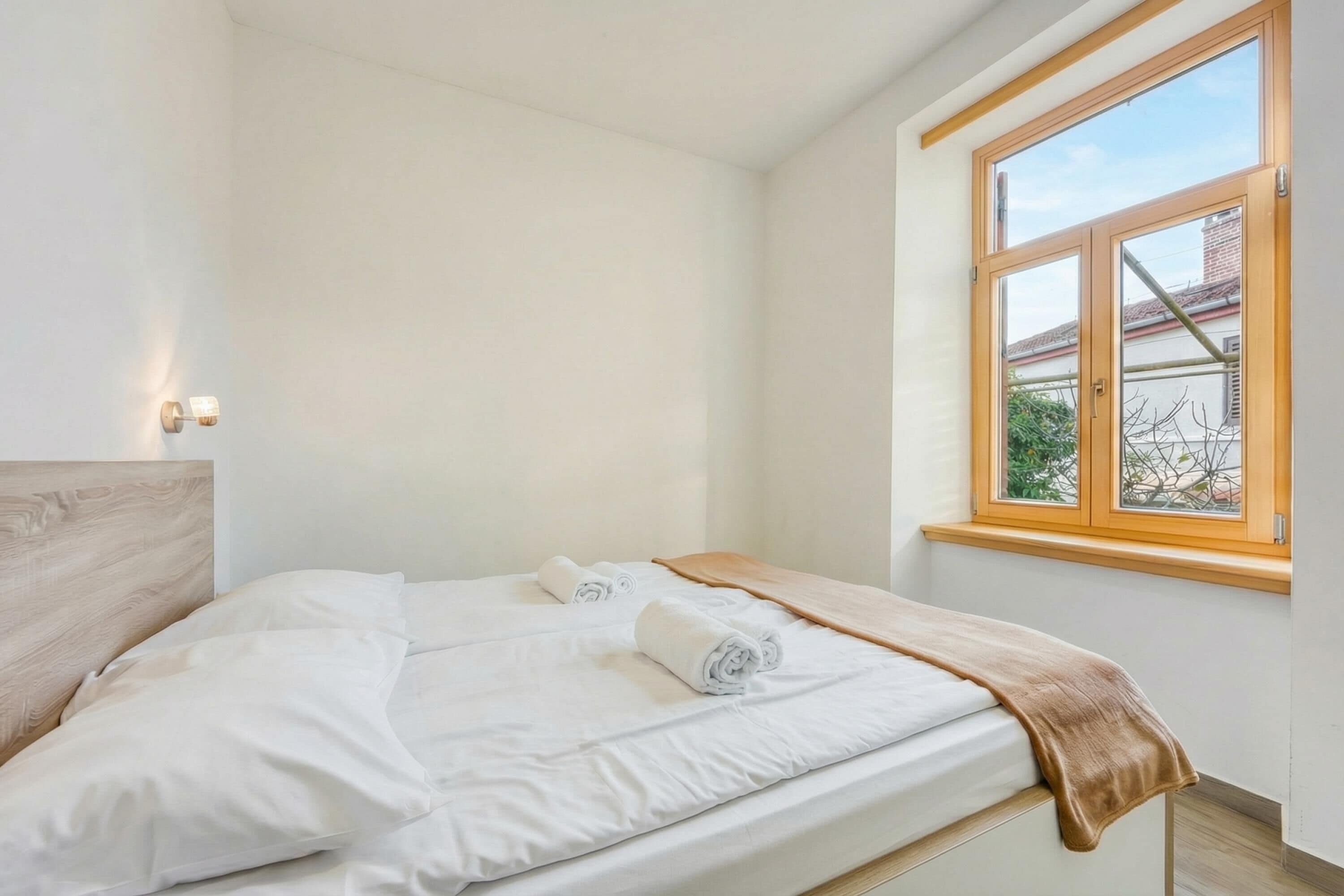 A bedroom with a large window, a wooden headboard, and neatly made beds.