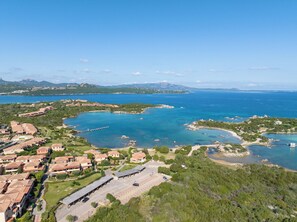 An aerial view of a coastal area with residential buildings, a marina, and clear blue waters. - Fantastico Baia de Bahas Residence Sea View 2 Bedroom Sleeps 6 (Golfo Aranci)