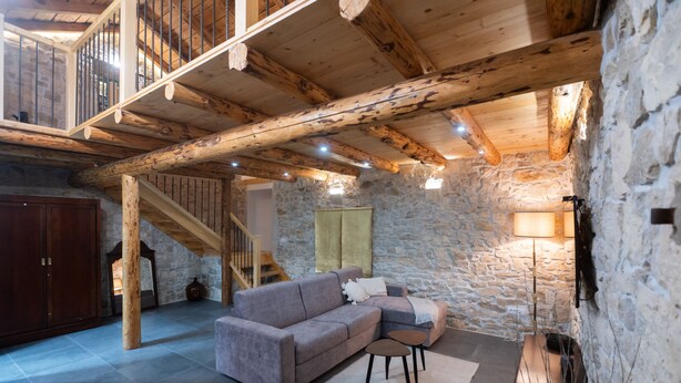 A rustic interior with a stone wall, wooden beams, a sofa, a small table, and a staircase. - Villa Jokić Dvori (Benkovac)