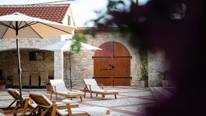 A stone-walled outdoor area with lounge chairs and a large wooden door. - Villa Jokić Dvori (Benkovac)