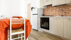 A compact kitchen with wooden cabinets, a white refrigerator, and a patterned backsplash. - Via Morghen 63 - Primo Piano (Naples)