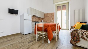 A compact living space with a kitchenette, a dining table, a sofa, and a television. - Via Morghen 63 - Primo Piano (Naples)