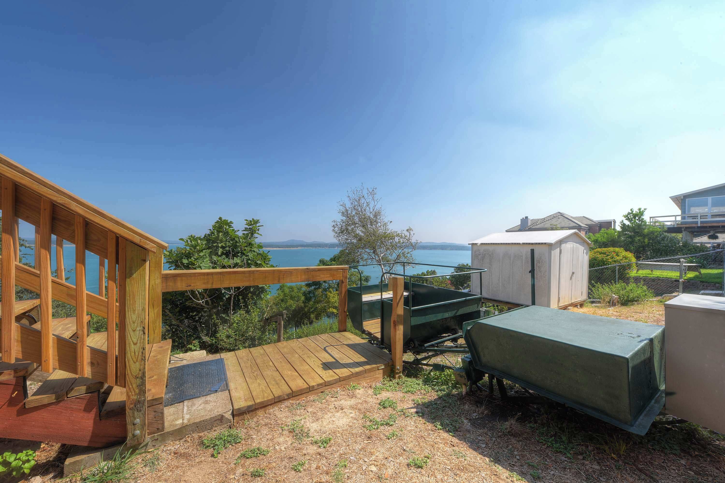 Un molo di legno con vista sul mare, un carretto verde e un piccolo deposito.
