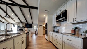 Una cocina moderna con armarios blancos, encimeras de granito y electrodomésticos de acero inoxidable.