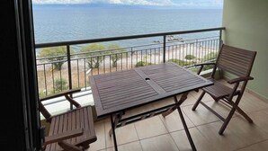 Un balcón con mesa y sillas, vista al mar y un ventilador de techo.