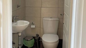 Un baño con inodoro, lavamanos y espejo.