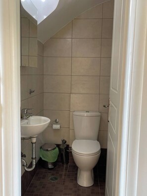A bathroom with a toilet, sink, and mirror. - The Pearl Seaview Apartment, 10sec Walk To The Sea (Messini)