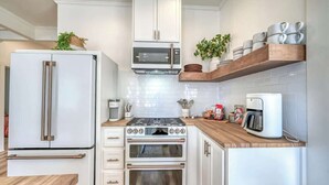 A compact kitchen with white cabinetry, a built-in microwave, a double oven, and a coffee maker on the countertop.