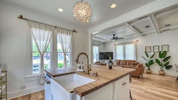 A spacious kitchen with a large island, wooden flooring, and a ceiling fan.