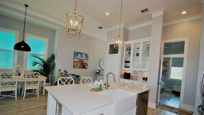 A modern kitchen with a large island, white cabinetry, and pendant lighting.